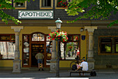 A couple sitting outside the pharmacy at the market square, Arnstadt, Thuringia, Germany