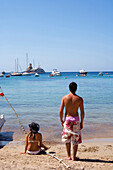 Young people standing at the beach, Cala Benirras, Ibiza, Balearic Islands, Spain
