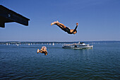 Menschen springen in den Ammersee, Bayern, Deutschland