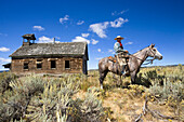 Cowboy mit Pferd vor altem Schulhaus, Wilder Westen, Oregon, USA