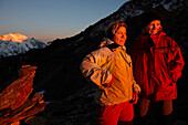 Two women, mountaineers watching the sunrise, dawn, Zwischenberg pass on the way from Almageller hut to the summit of the Weissmies 4023m, Wallis, Switzerland