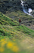 Wanderer unterwegs im Valle delle Mine, Wasserfall im Hintergrund, Livigno, Lombardei, Italien