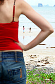Female tourist watching  two little girls at the beach, Krabi, Thailand; Asia