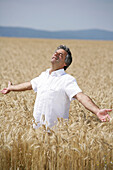 Man with outstreched arms standing in a corn field, Carinthia, Austria