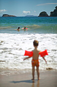 Mutter mit Töchtern (5 und 2,5 Jährige mit Schwimmhilfen), baden in Wellen am Hahei Beach, bei Hahei, Ostküste, Coromandel Peninsula, Nordinsel, Neuseeland