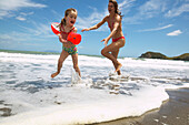 Mädchen (5 J.) spielt fangen mit ihrer Mutter, Strand von Port Jackson, Nordspitze der Coromandel Peninsula, Nordinsel, Neuseeland
