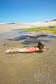 Mädchen badet in Wasserlauf an Westküste: Waimamaku Beach, Flußlauf ins Meer, bei Opononi / Omapere, Northland, Nordinsel, Neuseeland