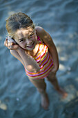 Mädchen horcht an gefundener Muschel, Strand in Pakawau, Golden Bay, Nordküste, Südinsel, Neuseeland