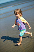 Girl (2 years) running along beach Kniepsand, Wittduen, Amrum island, North Frisian Islands, Schleswig-Holstein, Germany