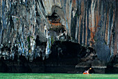 Canoe in front of limestone cliffs in the Bay of Phang Nga, Thailand