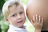 Junge (4-5 Jahre) berührt Babybauch seiner Mutter, Steiermark, Österreich