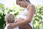 Boy (4-5 years) and pregnant mother embracing each other, Styria, Austria