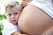 Junge (4-5 Jahre) umarmt Babybauch seiner Mutter, Steiermark, Österreich