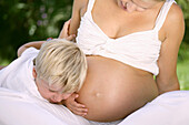 Boy (4-5 years) putting ear to pregnant mother's belly, Styria, Austria