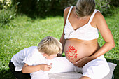 Boy (4-5 years) drawing sun on pregnant woman's belly, Styria, Austria