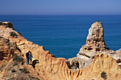 Ein Paar spazieren entlang Kalksteinfelsen, Algar Seco, Carvoeiro, Algarve, Portugal