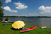 rubber dinghy, sunshade, kayak and bathers at shore of lake Staffelsee, Upper Bavaria, Bavaria, Germany