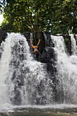 Ein Mann springt über den Wasserfall der Rochester Falls, nahe Surinam, Savanne District, Mauritius, Indischer Ozean