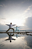 Couple practising yoga at Lake Starnberger, Muensing, Bavaria, Germany, MR