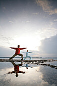 Mann und Frau machen Yoga, Yogaübung Der Krieger, Spiegelung im Wasser, Buchscharn, Starnberger See, Bayern, Deutschland
