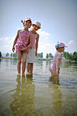 Three girls (3-8 years) standing in water, Lake Staffelsee, Upper Bavaria, Germany