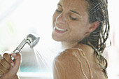 Mid adult woman using shower in bath, Styria, Austria