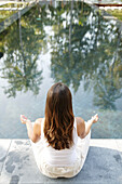 Frau beim Meditieren am Pool, Wellness, Entspannung, Gesundheit