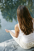 Frau beim Meditieren am Pool, Wellness, Entspannung, Gesundheit
