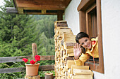Woman looking out of a window and waving, Heiligenblut, Hohe Tauern National Park, Carinthia, Austria