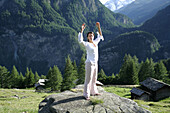 Woman practising yoga on a rock, Heiligenblut, Hohe Tauern National Park, Carinthia, Austria
