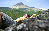 Woman lying on grass, mountains in background, Heiligenblut, Hohe Tauern National Park, Carinthia, Austria
