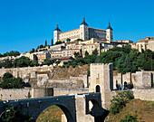 Alcántara bridge and Alcázar fortress dominating the city in background. Toledo. Spain