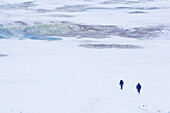 Zwei Männer gehen über Schneefläche, Island