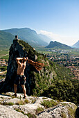 Kletterer auf Gipfel wirft ein Seil, Arco, Trentino-Südtirol, Italien