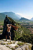 Climber on summit throwing a rope, Arco, Trentino-Alto Adige/Südtirol, Italy