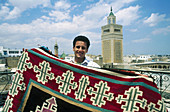Carpet seller. Souq. Zitouna mosque at the back (XVIIth century). Tunis. Tunisia.