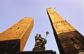 Garisenda and Asinelli towers and statue of St. Petronio. Bologna. Italy