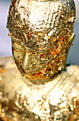 Close up on Buddha statue plated with gold leaves.