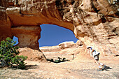 Hiker passing through an arch. Arches National Park. Utah. USA