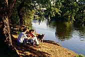 Three young people and a dog having a picnic near  river, Witten, Ruhr Valley, Ruhr, Northrhine Westphalia, Germany