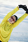 Woman stretching in snow, smiling at camera, Styria, Austria
