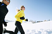 Zwei Frauen joggen über verschneiten Weg, Steiermark, Österreich