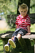 Boy (4-5 years) sitting on a bench, Styria, Austria