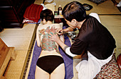 Tattoo master Taketo Omiya working on a yakuza s back. Ikebukuro, Tokyo, Japan