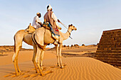 Bedouins on their camels by Meroe, city of ancient Cush (Kush) on the East Bank of the Nile: Meroe necropolis has more than 200 pyramids, the meroitic civilization followed Napata era starting from 270 BC. Upper Nubia, Blue Nile state, Sudan