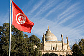 Tunisian flag. The Saint-Louis cathedral at back. Archeological Museum presenting mosaics, sculptures and other items from the excavations of the ancient city. Carthage . Tunisia