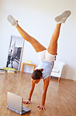 Woman doing exercises and portable computer on the floor