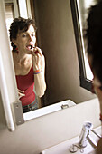 Frau mit Lippenstift vor dem Spiegel