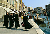 Priests hurrying along canal. Venice. Italy
