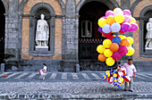 Girl playing football and balloons seller in front of Royal Palace. Naples. Italy